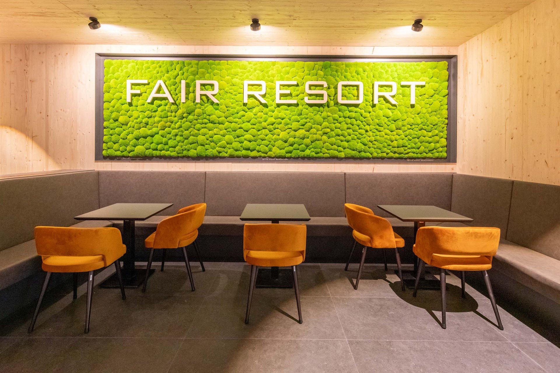 Urlaub in Jena: mein Fair Resort Moderner Sitzbereich mit orangefarbenen Stühlen und grünem FAIR RESORT Schriftzug an der Wand