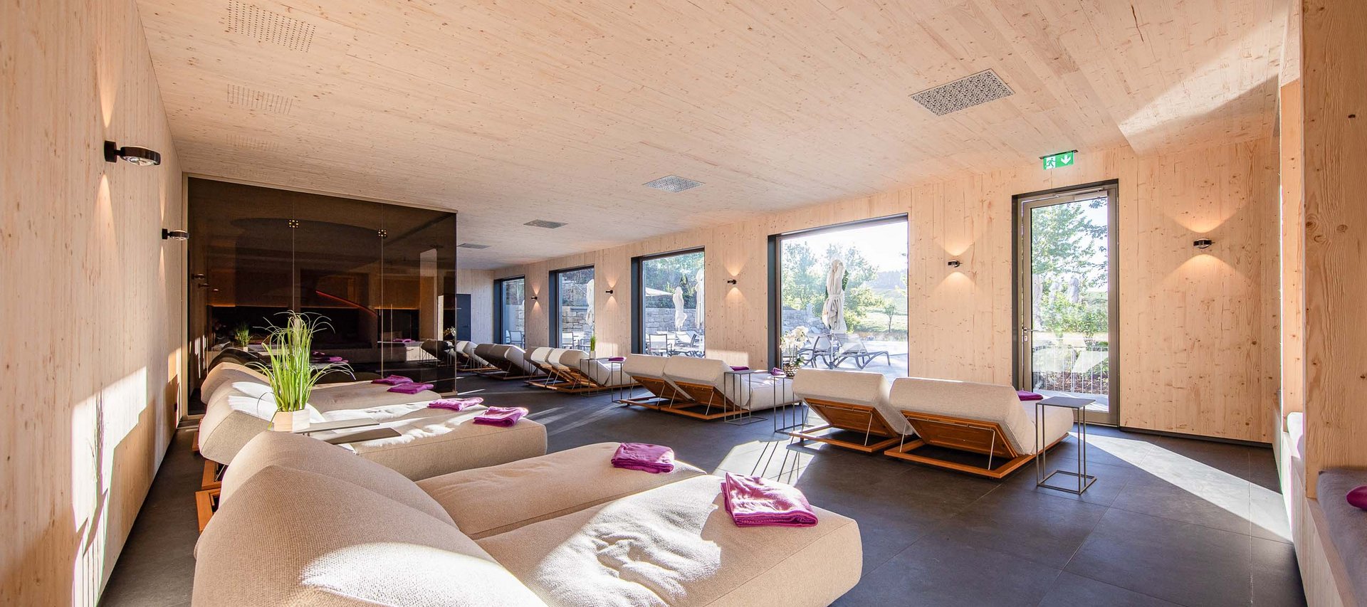 Wellnesshotel in Jena? Heller Wellness-Ruheraum mit Liegen und großen Fenstern zum Außenbereich