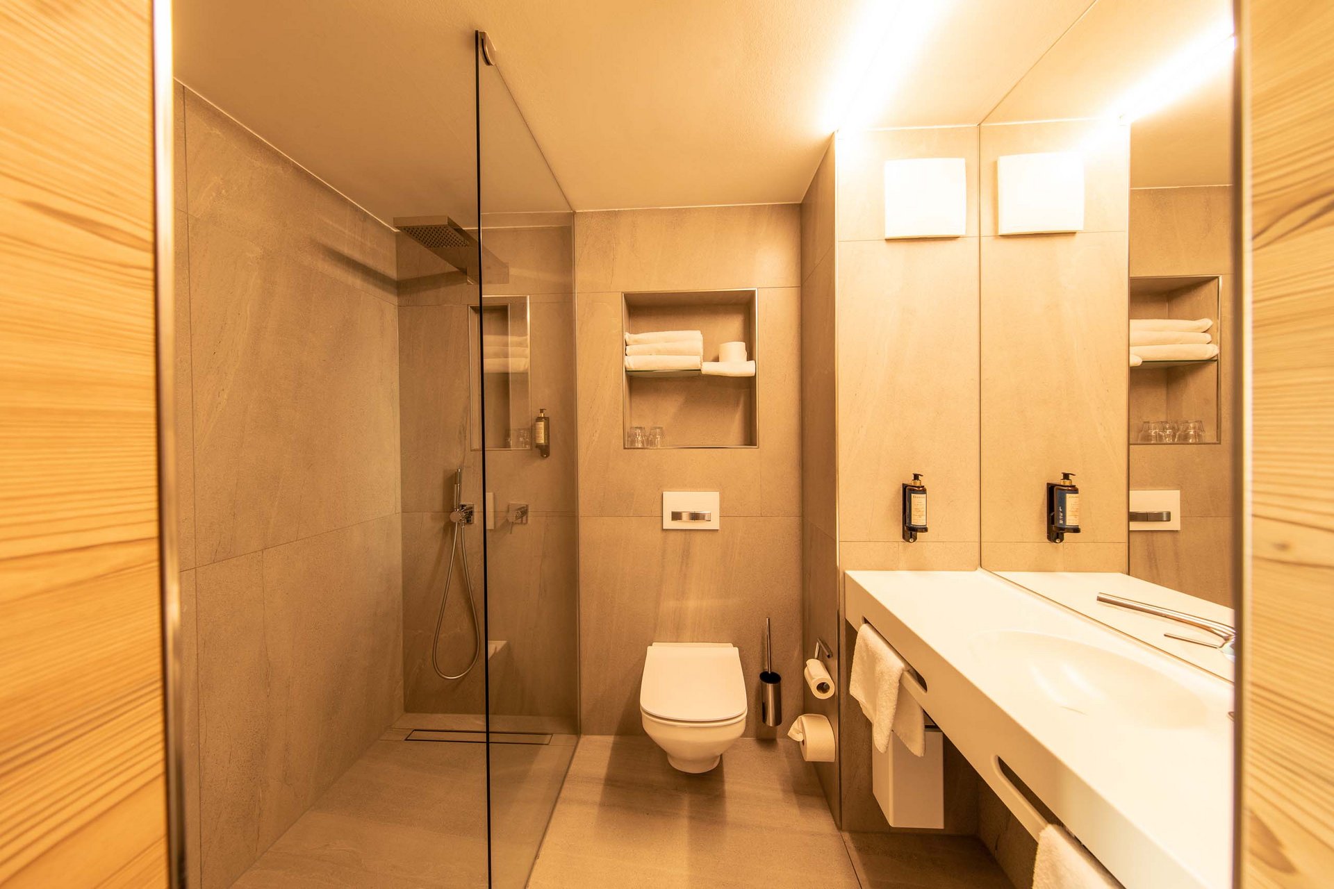 Dreibettzimmer Modernes Badezimmer mit Dusche, Toilette und Waschbecken in warmen Tönen