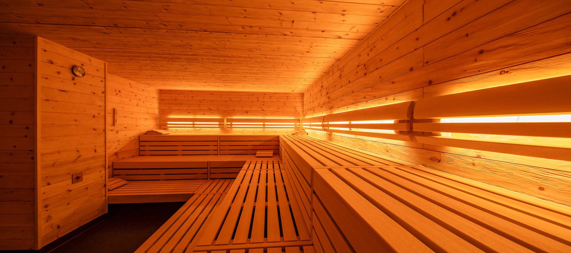 Wellnesshotel in Jena? Innenraum einer modernen Holzsauna mit Bänken und warmem Licht