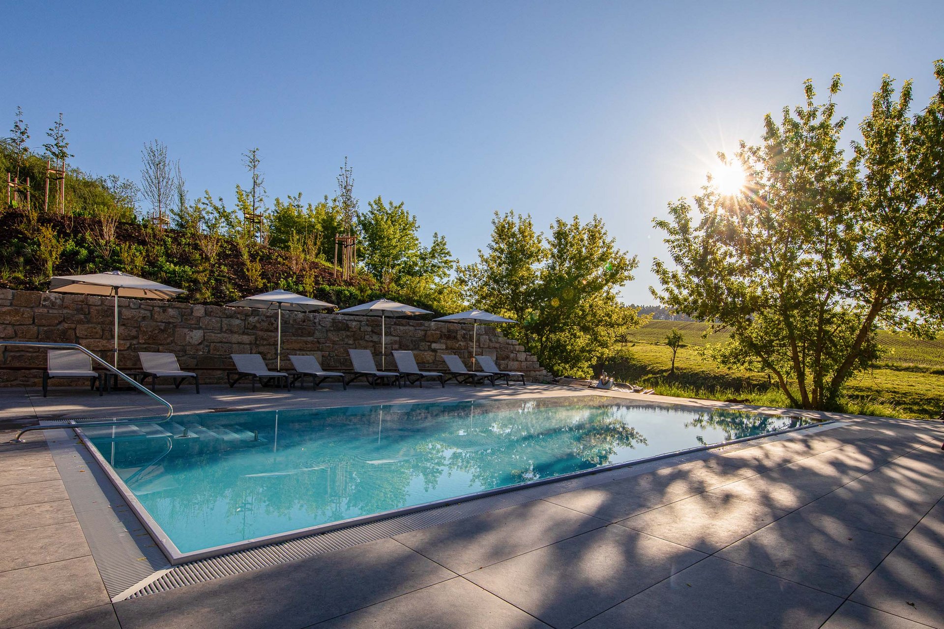 Das Sporthotel in Jena Freizeitpool mit Liegestühlen und Sonnenschirmen in sonniger ländlicher Umgebung