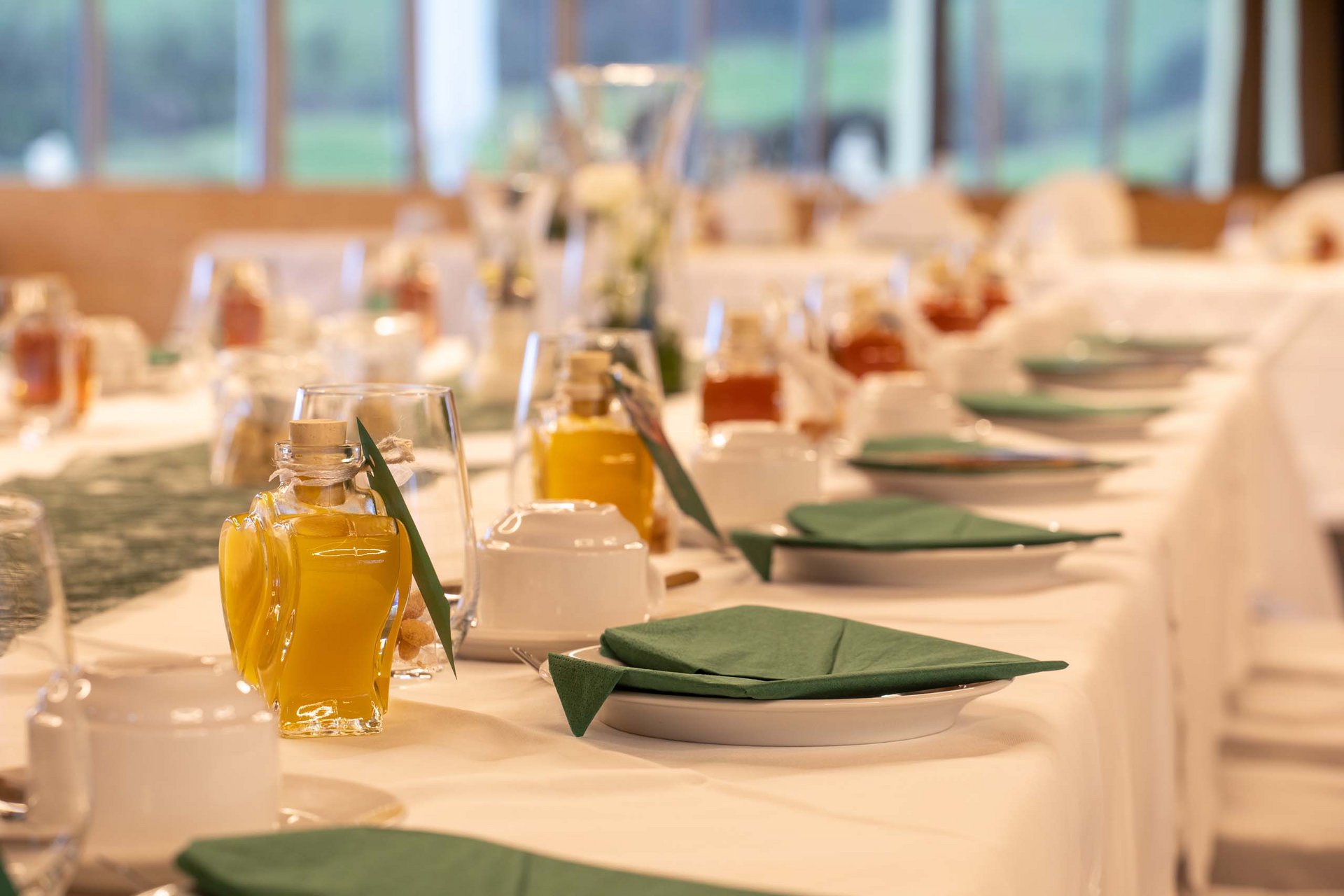 Das Event- und Tagungshotel in Jena Festlich gedeckter Tisch mit grünen Servietten und kleinen Flaschen mit gelbem Inhalt