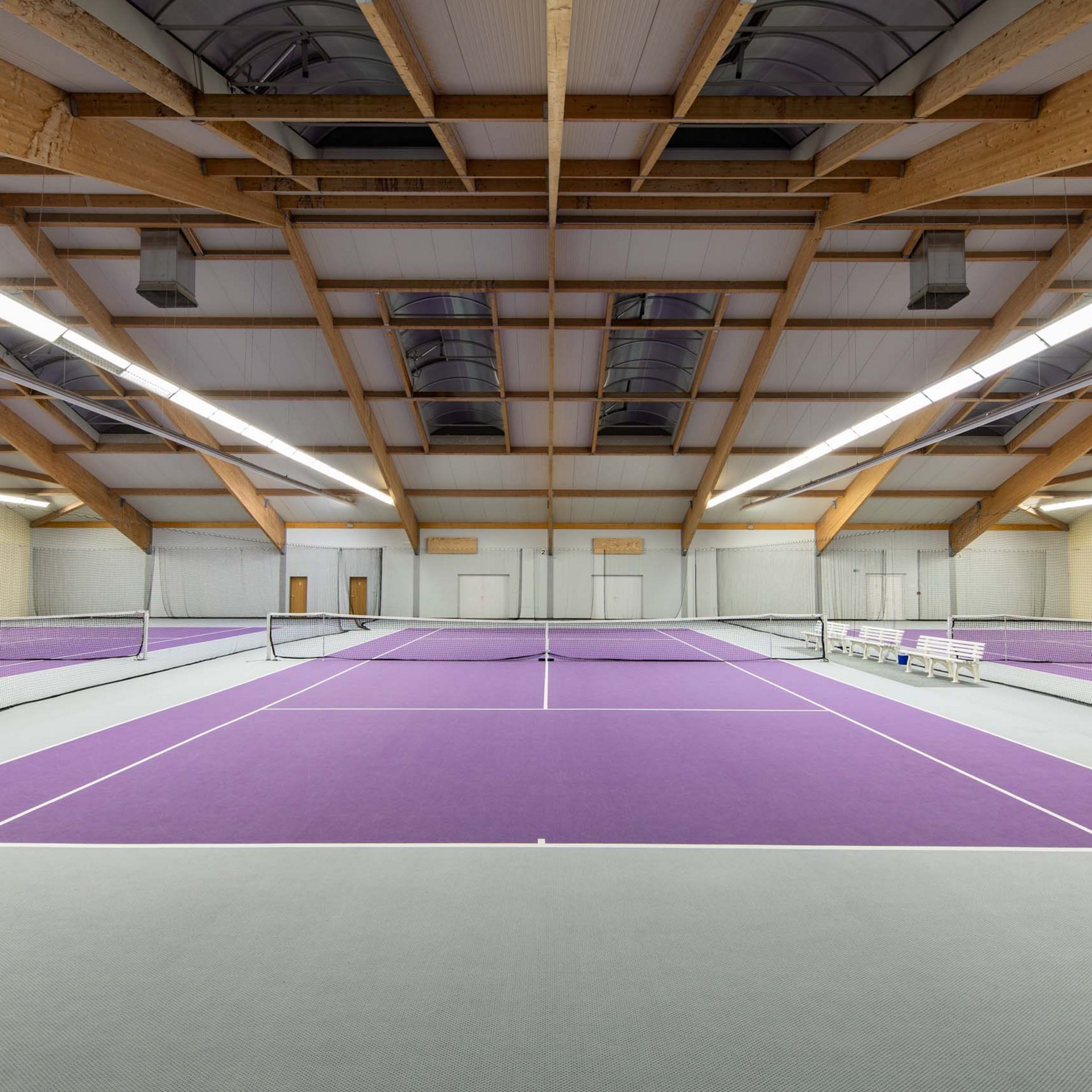 Das Sporthotel in Jena Leerer Hallen-Tennisplatz mit lila Bodenbelag und Holzbalkendecke