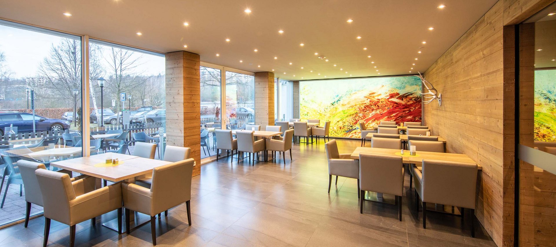 Ein Hotel in Jena mit All-inclusive-Verpflegung Modernes Restaurant mit Stühlen, Tischen und großen Fenstern mit Außenblick