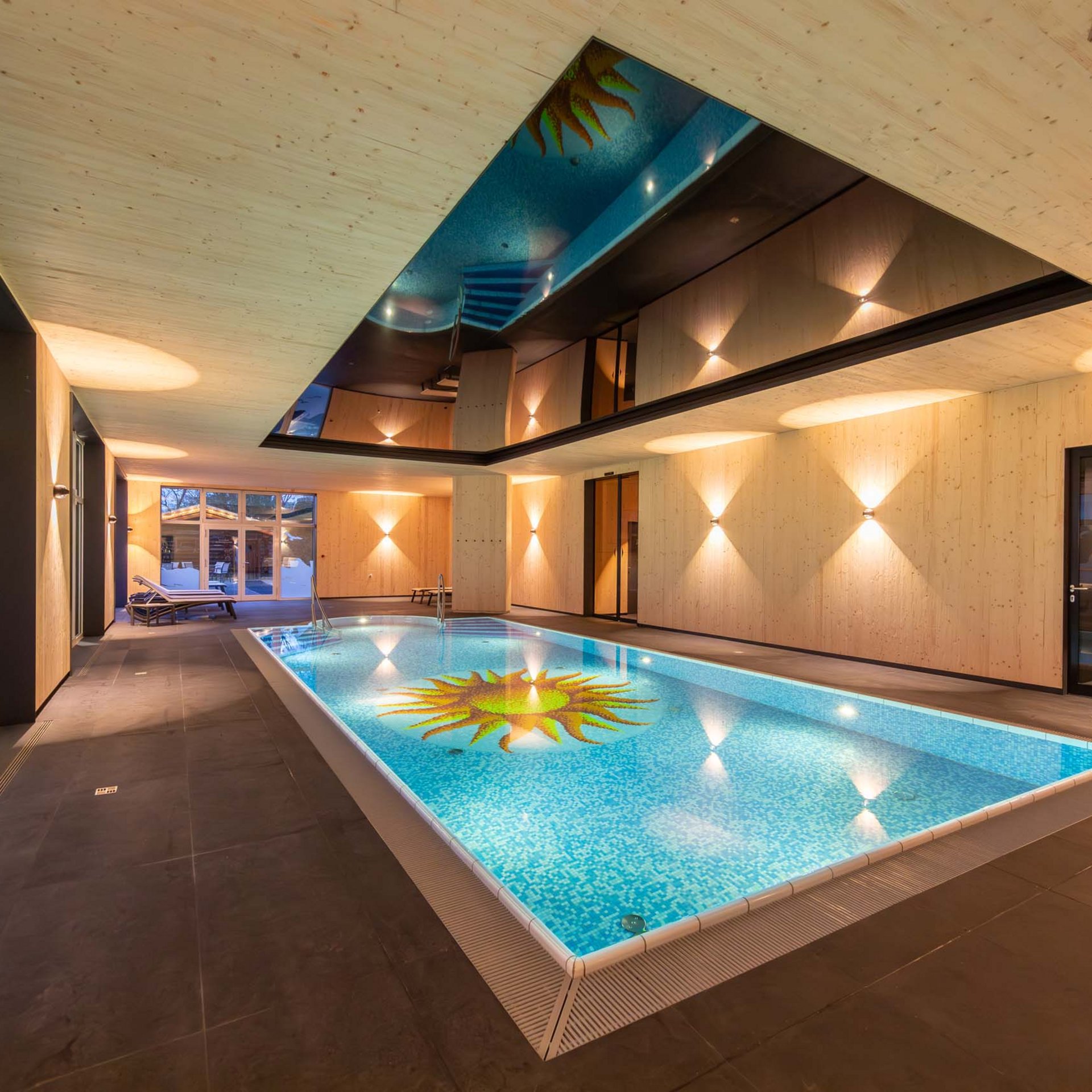 Wellnesshotel in Jena? Hallenbad mit blauem Wasser und Sonnenmosaik auf Boden und Decke