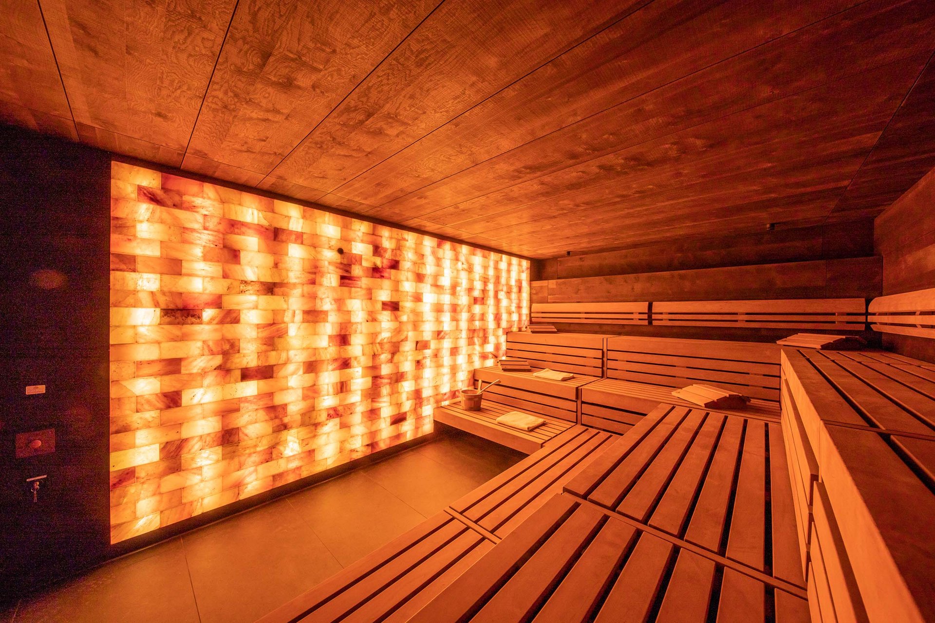 Wellnesshotel in Jena? Innenansicht einer modernen Sauna mit Holzverkleidung und beleuchteter Salzsteinwand