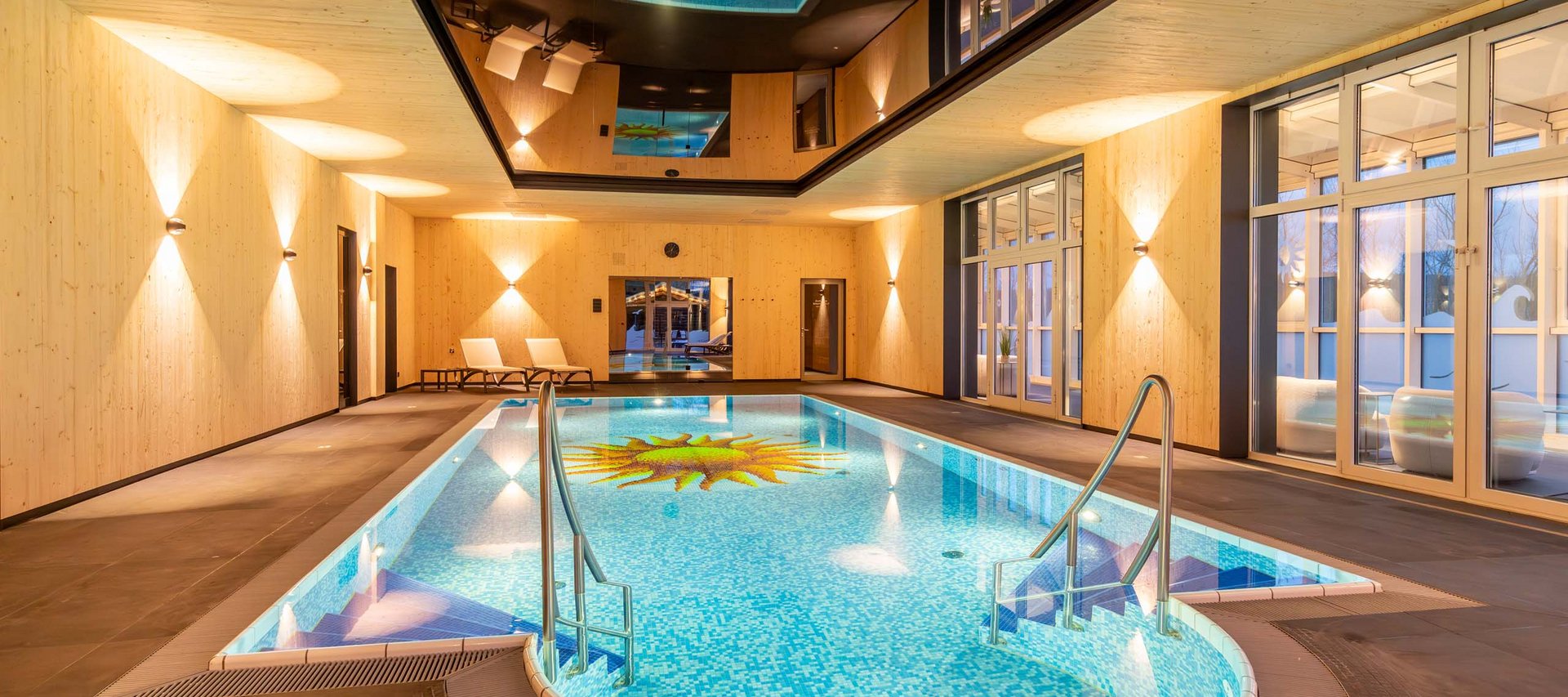 Wellnesshotel in Jena? Innenansicht eines modernen Hallenbads mit Holzverkleidung und Sonnendesign im Becken
