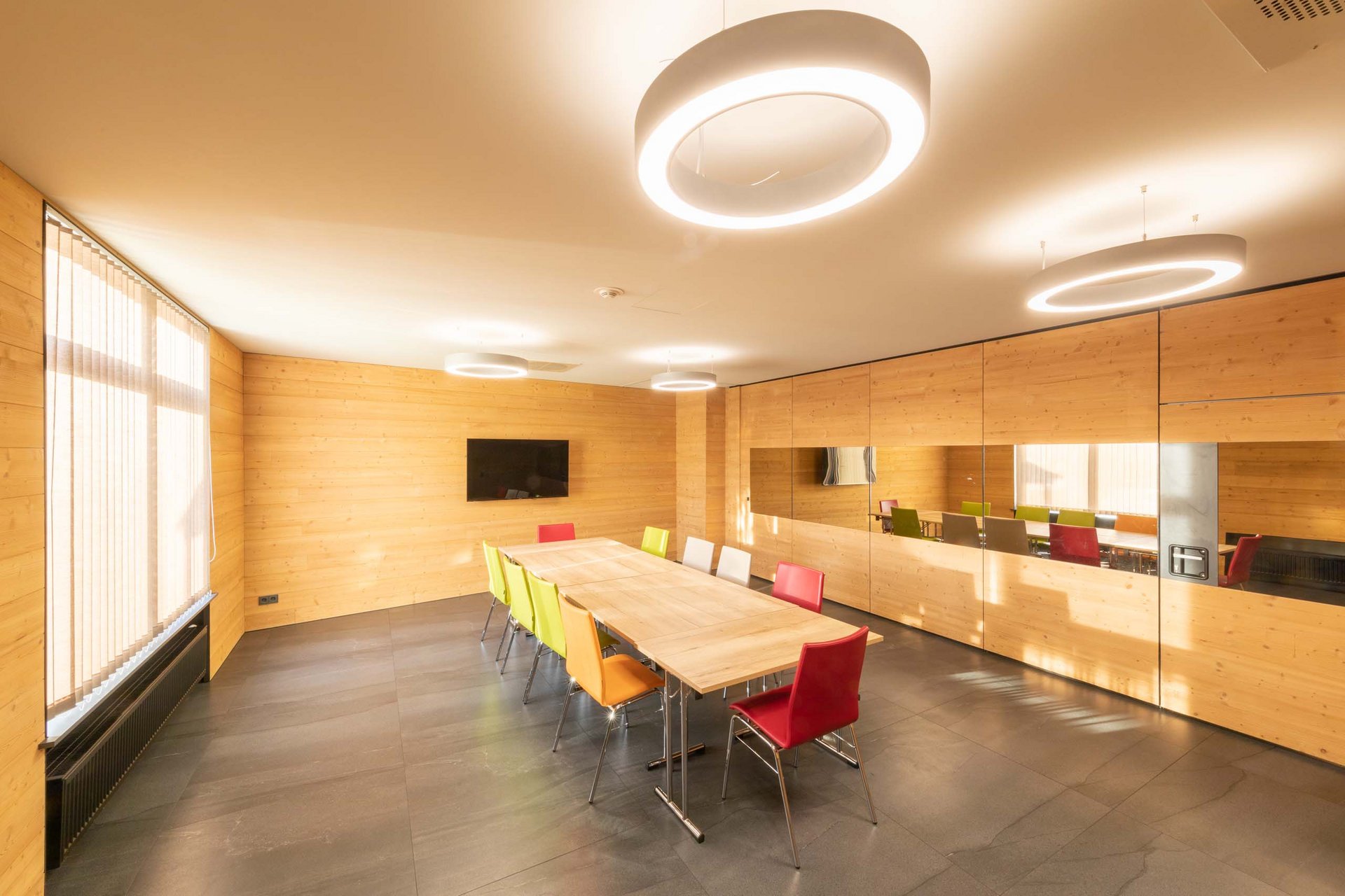 Urlaub in Jena: mein Fair Resort Moderner Besprechungsraum mit Holzwänden und bunten Stühlen
