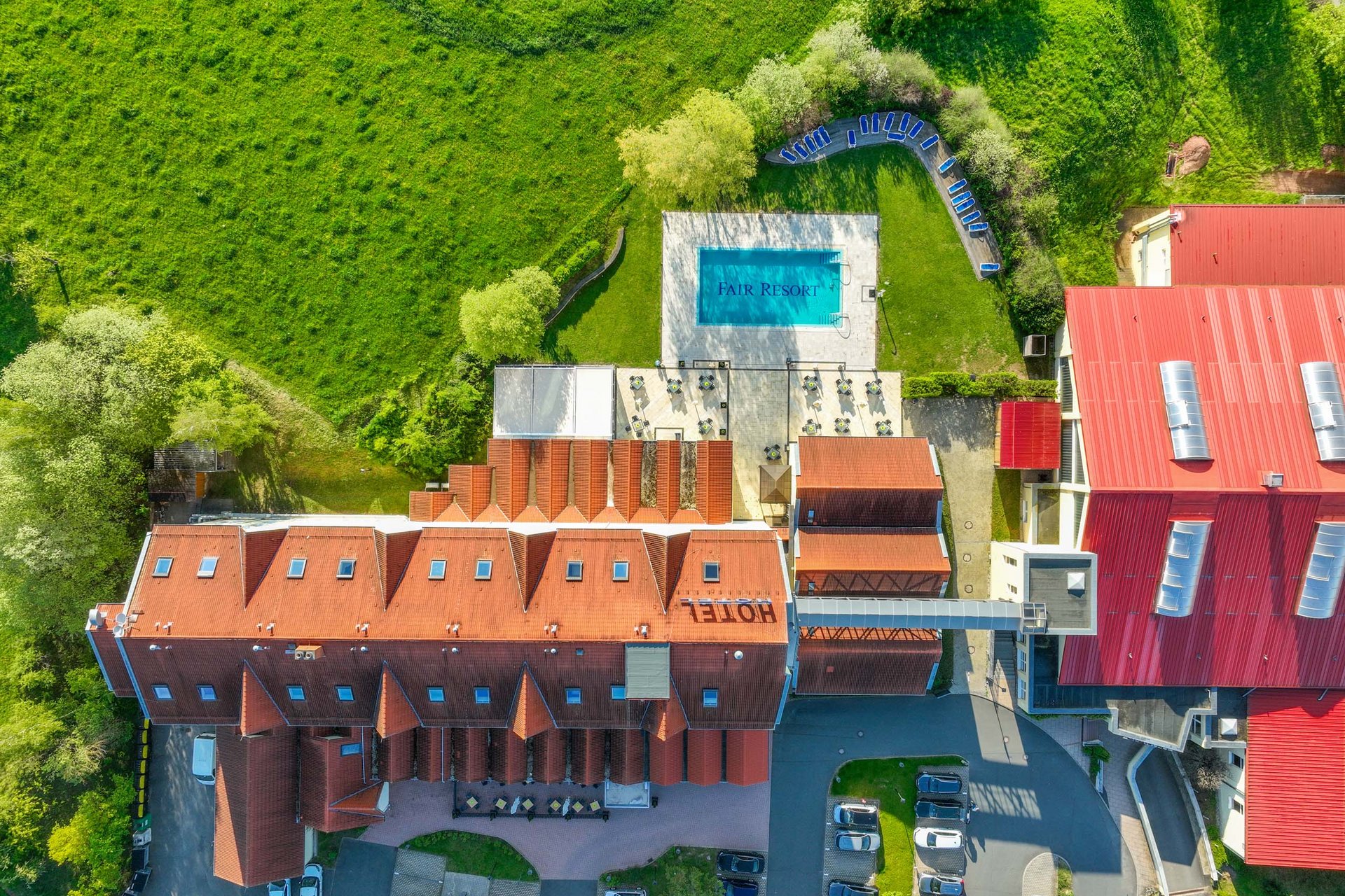 Urlaub in Jena: mein Fair Resort Luftaufnahme eines Hotels mit Pool und grüner Wiese