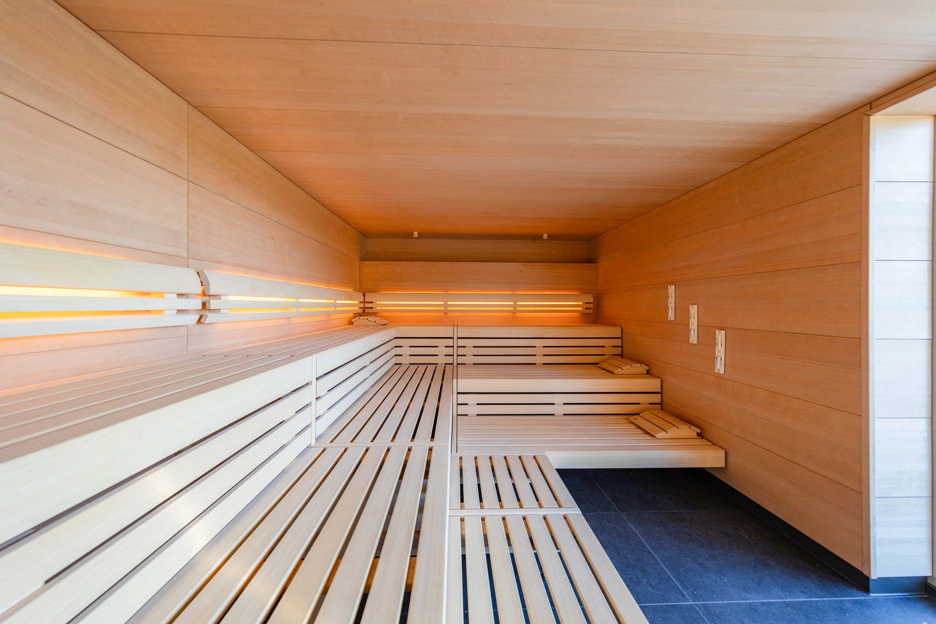 Das Sporthotel in Jena Moderner Saunaraum mit hellen Holzlattenbänken und indirekter Beleuchtung