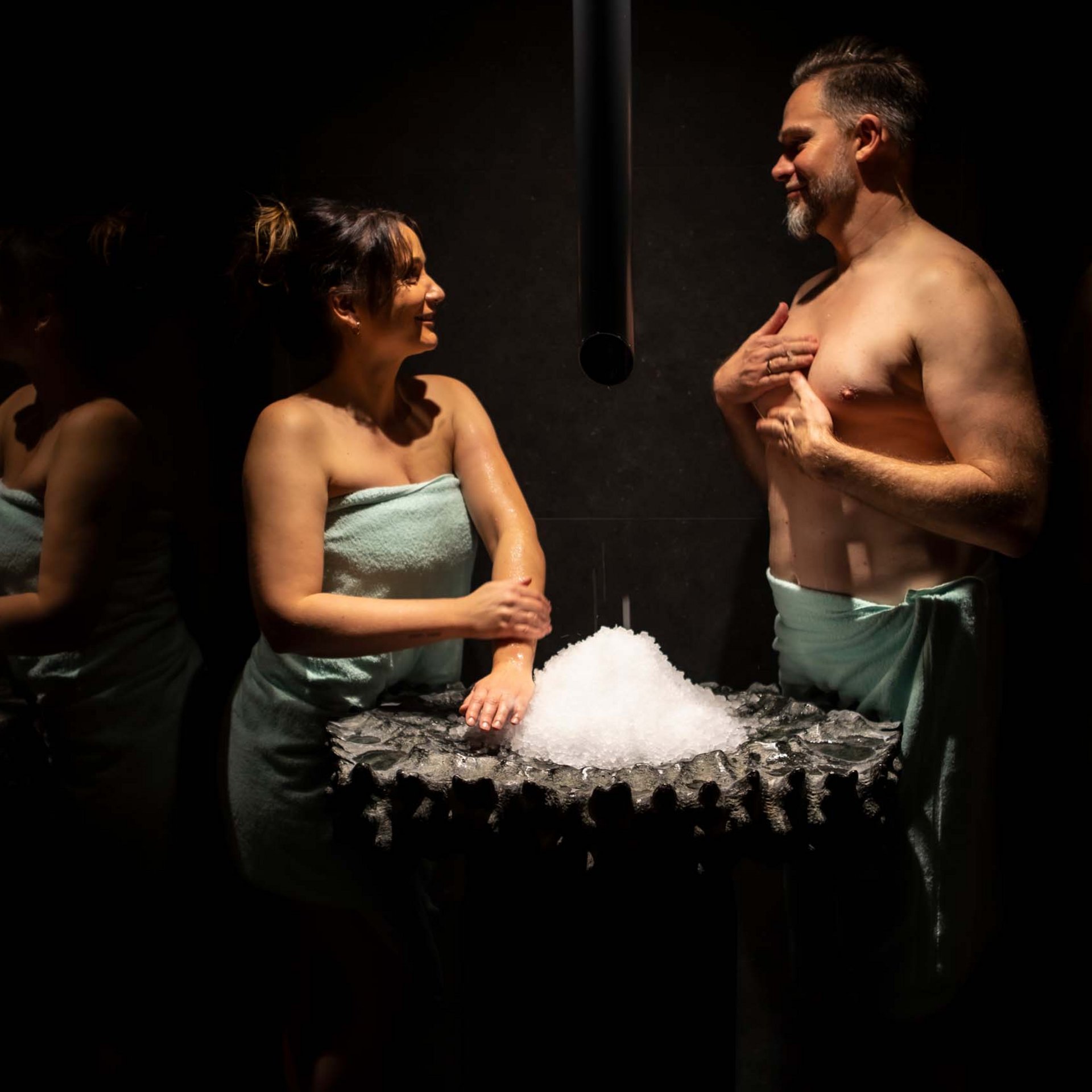Wellnesshotel in Jena? Frau und Mann in Handtüchern stehen vor Eisbrunnen im dunklen Raum