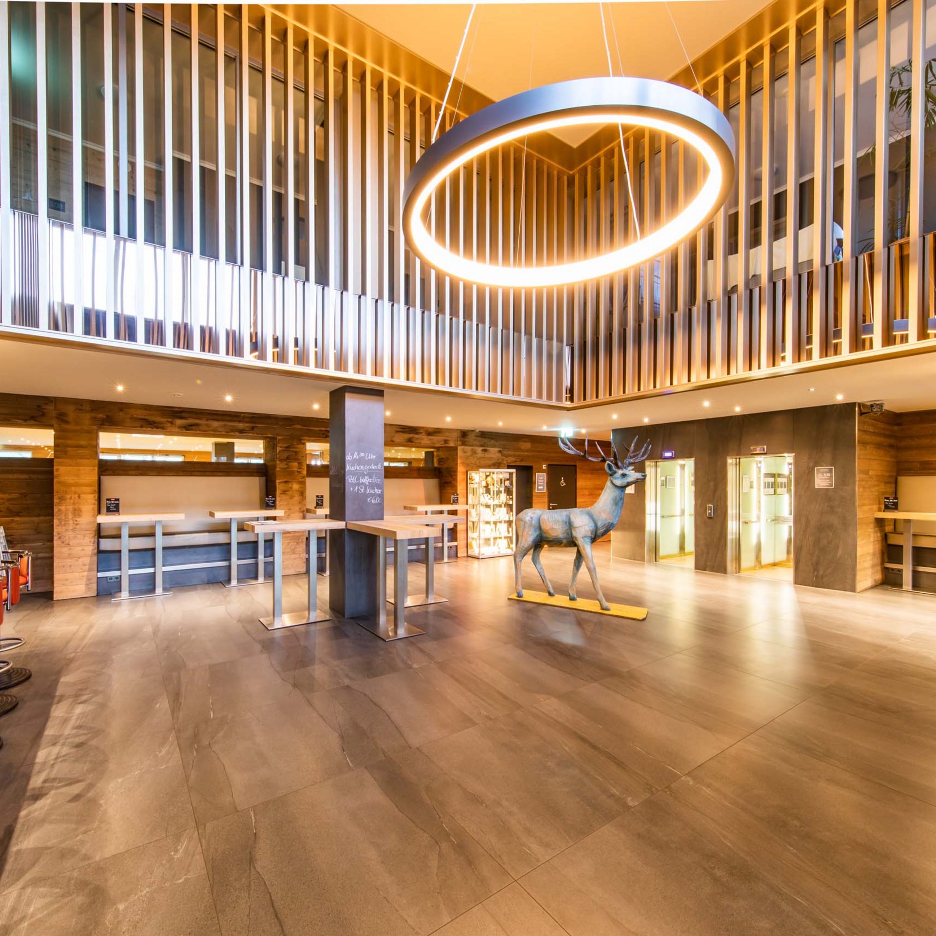 Das wohl beste Wellnesshotel in Thüringen Helle Hotellobby mit modernem Kronleuchter und Hirschskulptur in der Mitte
