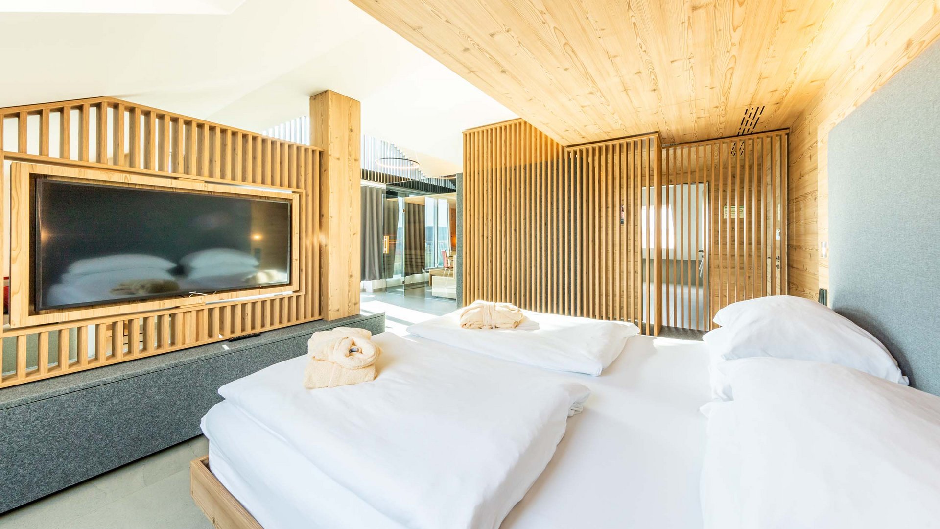 Das wohl beste Wellnesshotel in Thüringen Helles Schlafzimmer mit Holzverkleidungen und großem Fernseher