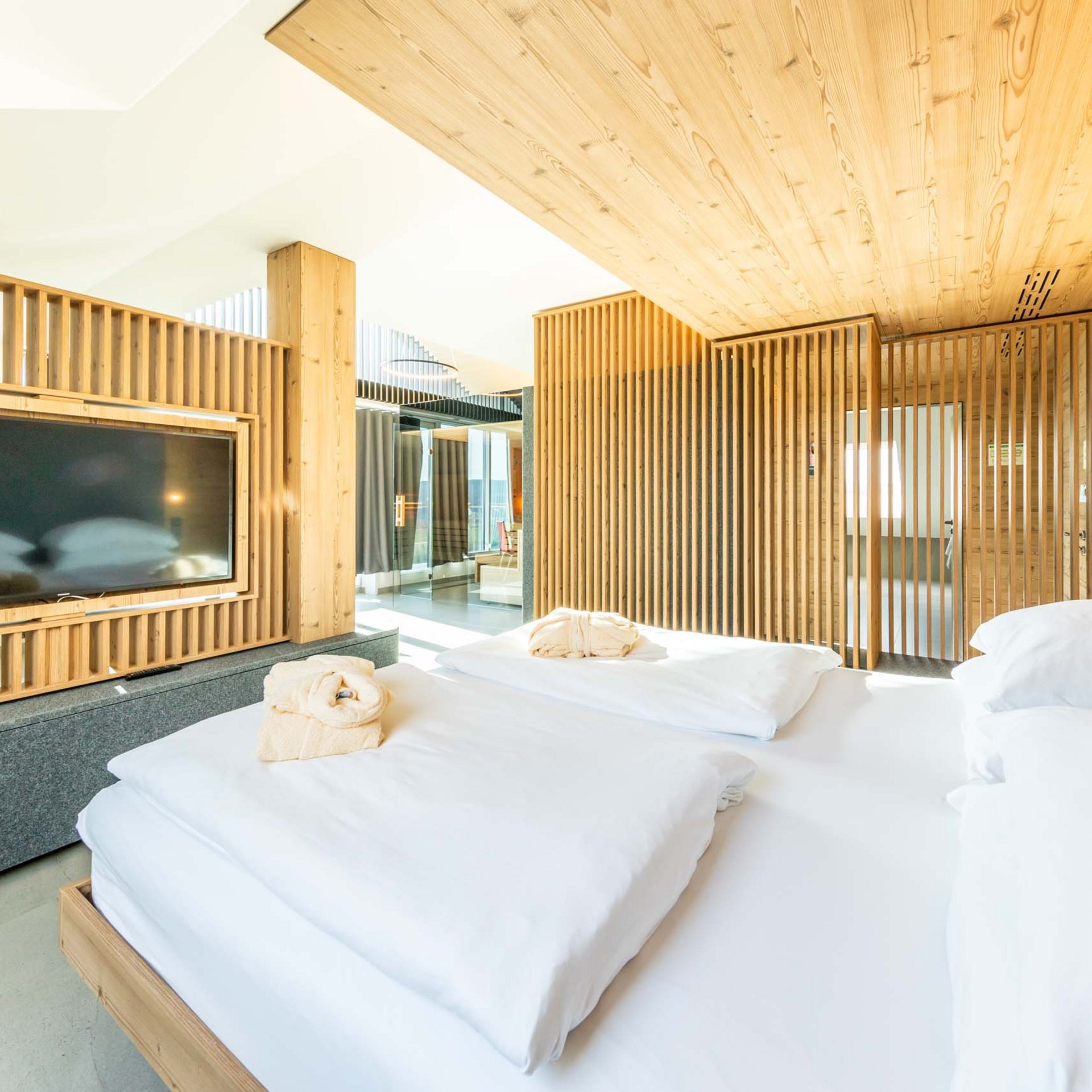 Das wohl beste Wellnesshotel in Thüringen Helles Schlafzimmer mit Holzverkleidungen und großem Fernseher