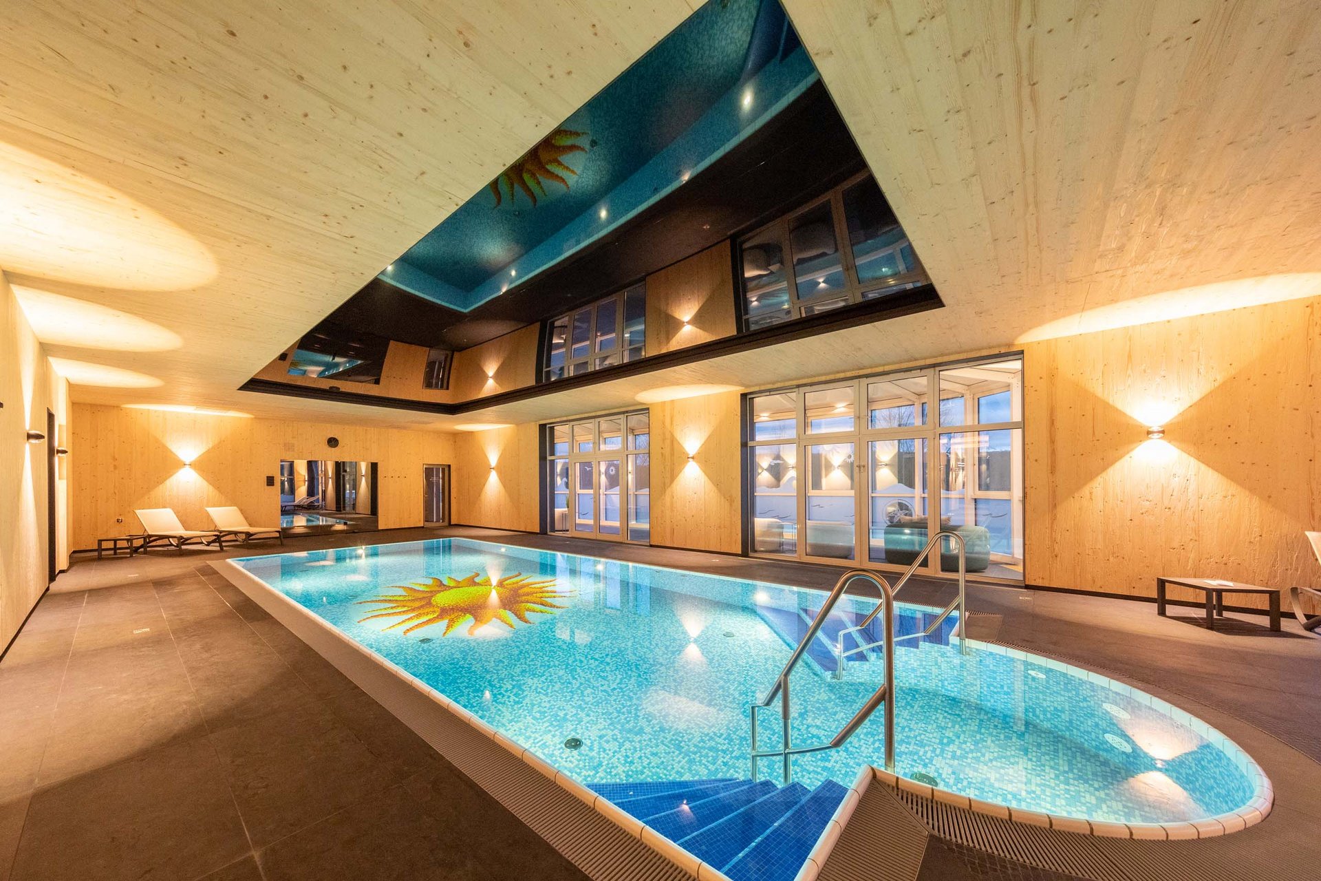 Das wohl beste Wellnesshotel in Thüringen Innenpool mit Holzverkleidung, Lounge-Stühlen und beleuchtetem Schwimmbecken