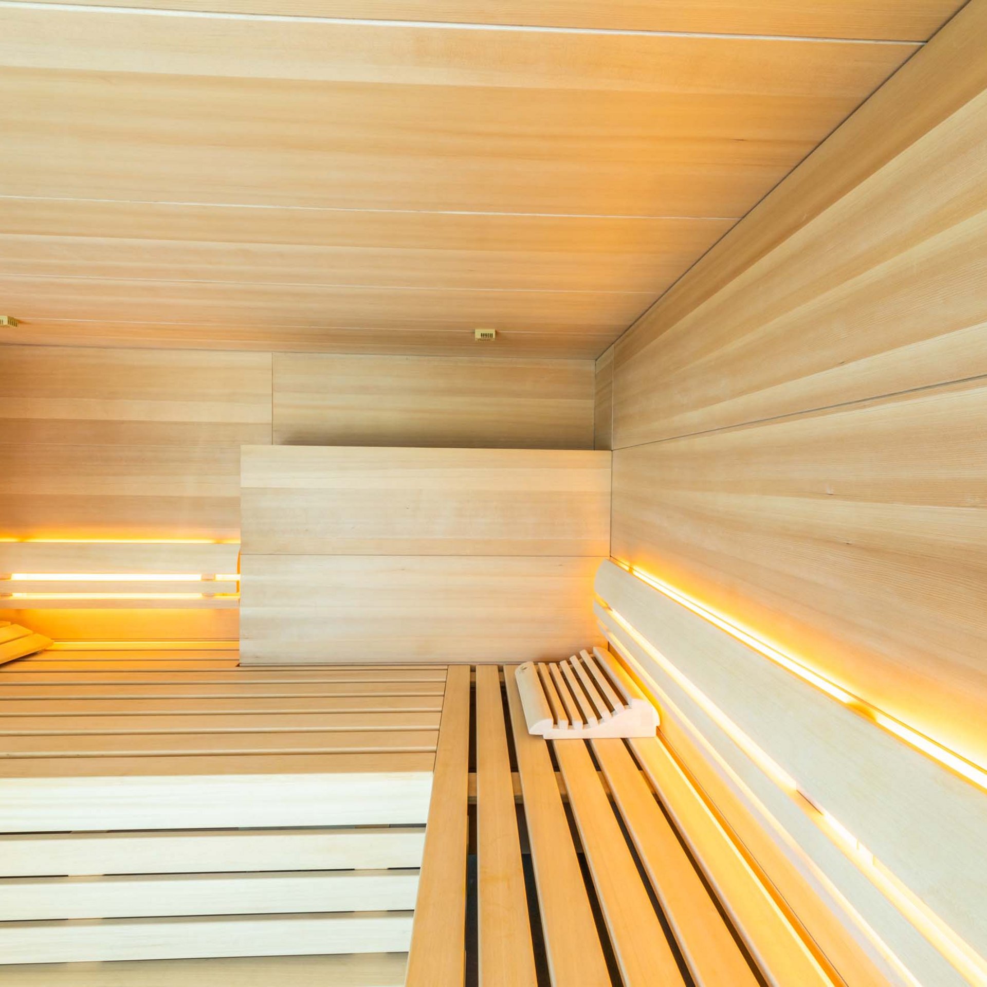 Wellness-Suite Moderne finnische Sauna mit hellem Holz und indirekter Beleuchtung