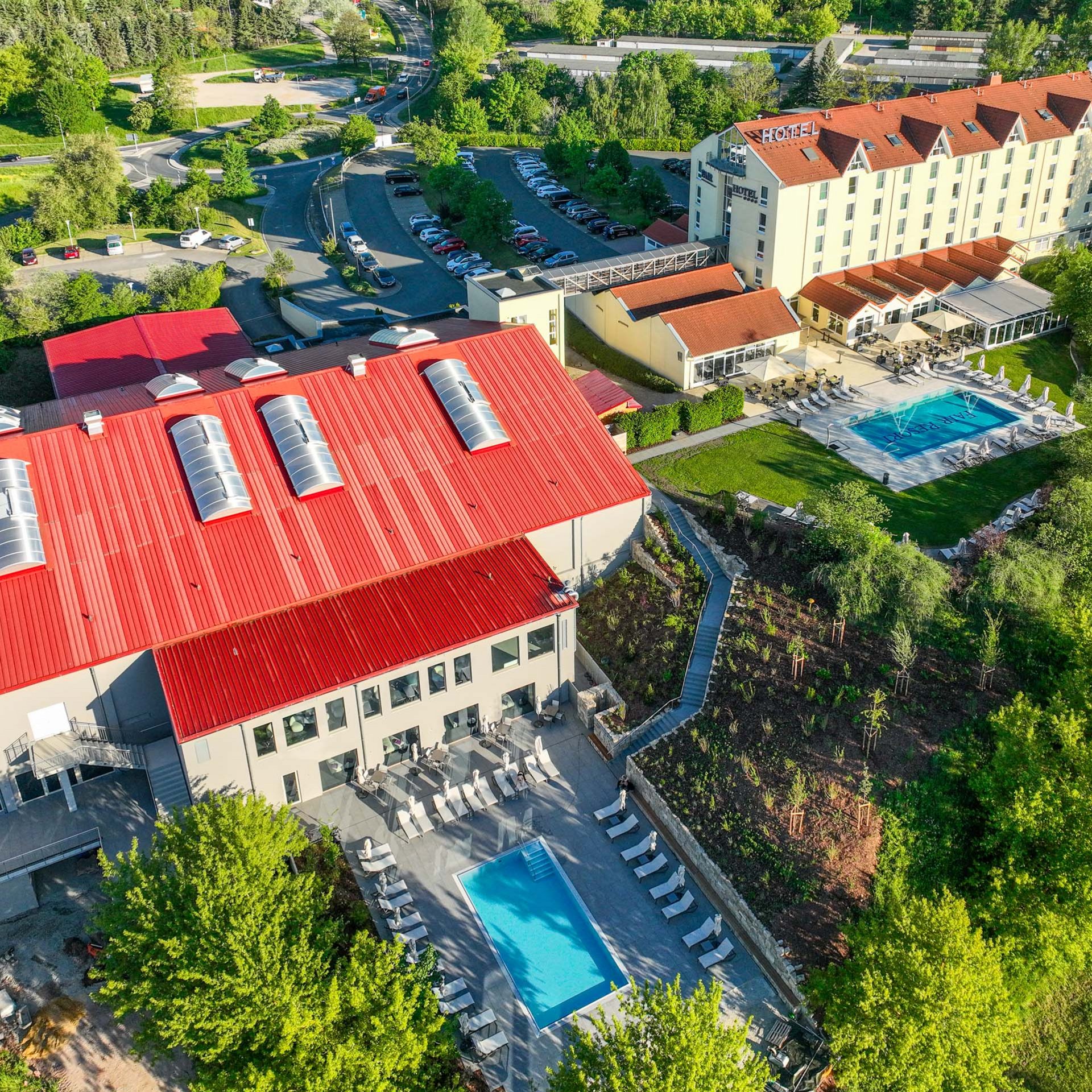 Das wohl beste Wellnesshotel in Thüringen Luftaufnahme eines Hotels mit rotem Dach, zwei Swimmingpools und viel Grün