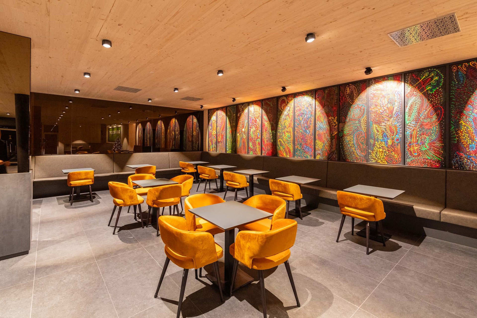 Das wohl beste Wellnesshotel in Thüringen Moderner Sitzbereich mit orangen Stühlen und bunter Wandkunst in gemütlichem Lokal