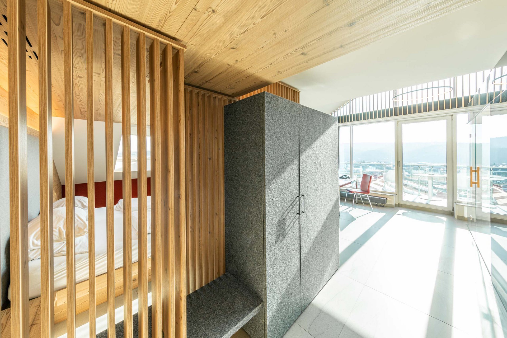 Wellness-Suite Modernes Zimmer mit Holzakzenten, grauem Schrank und großer Fensterfront