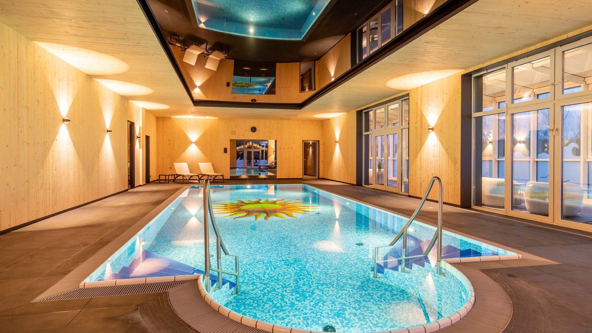 Das wohl beste Wellnesshotel in Thüringen Innenansicht eines modernen Hallenbads mit Holzverkleidung und Sonnendesign im Becken