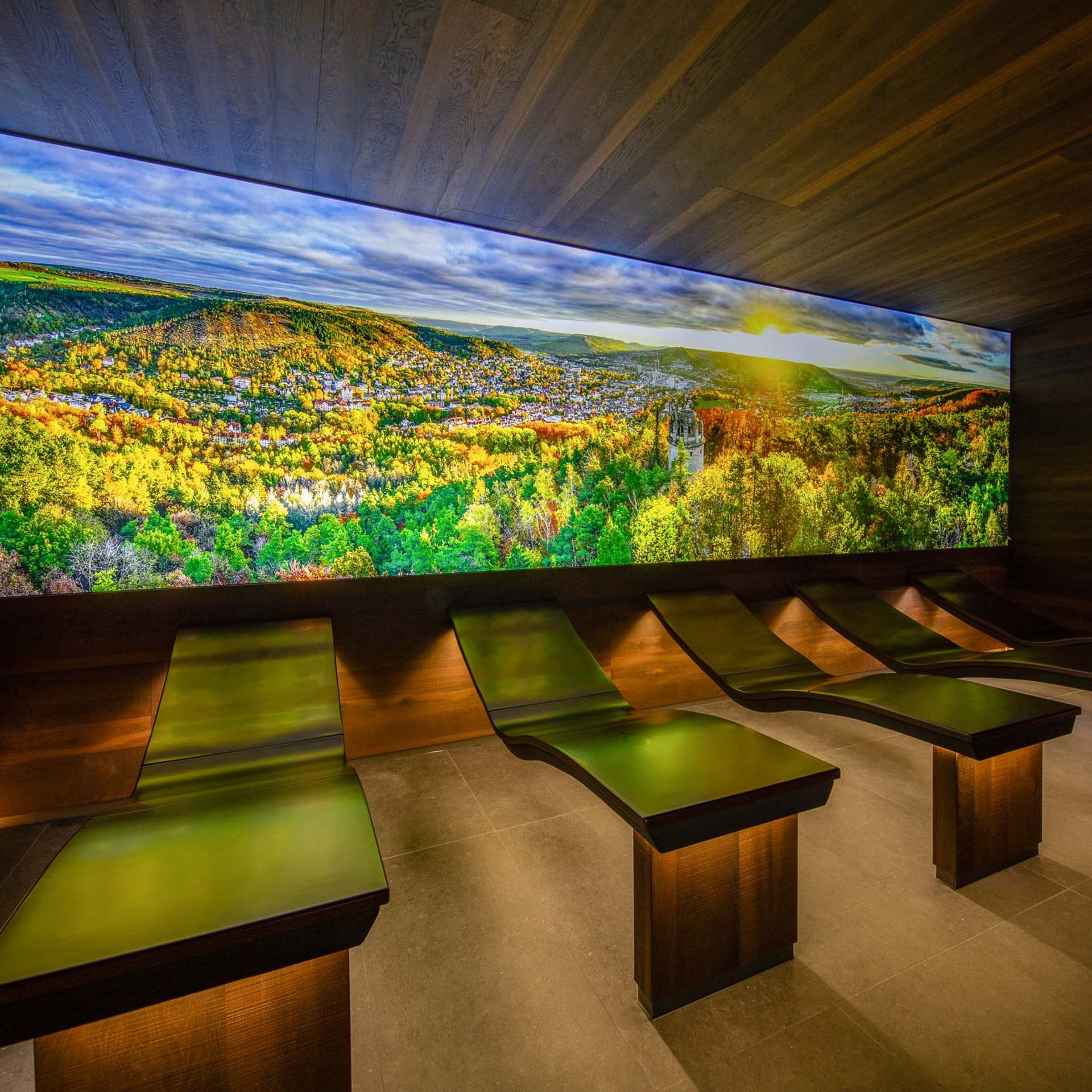 Das wohl beste Wellnesshotel in Thüringen Entspannungsraum mit Liegen und großem Wandbild eines herbstlichen Waldes